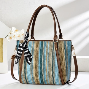 Striped woven tote bag with leather handles and decorative scarf on white background