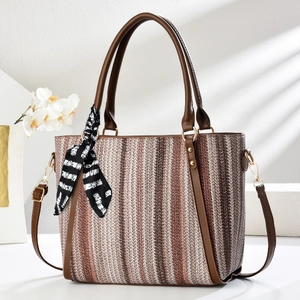 Large striped straw tote bag with faux leather straps and a decorative silk scarf