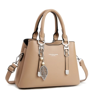 Sac à main élégant en cuir abricot avec breloque feuille d'argent et perle sur blanc