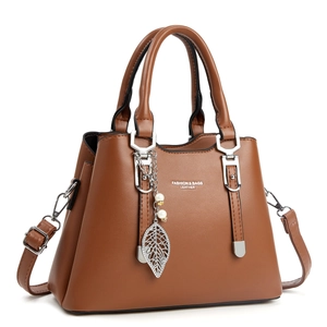 Détail du sac à main marron avec ferrures argentées et pendentif feuille avec perles