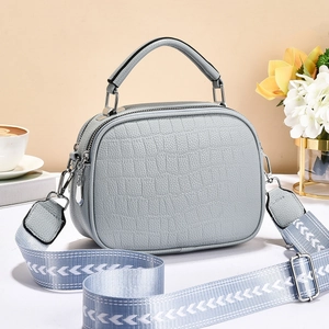 Sac à main bleu clair avec motif texturé et large bandoulière tissée dans un décor chic