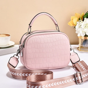 Détail du sac à main rose gaufré crocodile avec double fermeture et bandoulière tissée