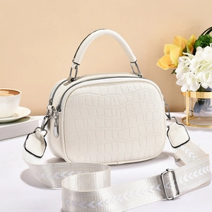 Détail du sac blanc à motif crocodile avec double zip et bandoulière géométrique
