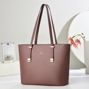 Close-up of deep red-brown tote bag with lychee texture and gold brand logo