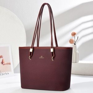 Detailed macro view of burgundy woven texture and gold buckles on a stylish tote bag