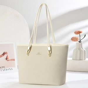 Detail of cream woven texture tote bag with golden metal hardware and long straps