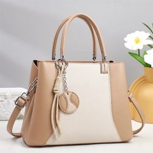 Chic beige leather and canvas patchwork handbag with cross-body strap and charm