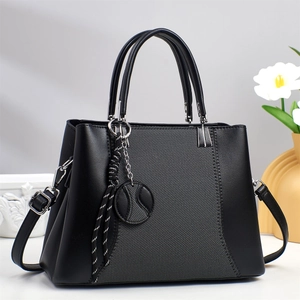 Elegant black synthetic leather handbag with grey fabric panel and woven charm accessory