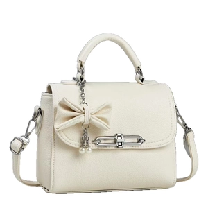 Minimalist beige textured leather crossbody bag with decorative bow and pearl charms