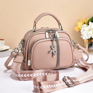 Detail of dusty pink pebbled leather bag with woven strap and silver puppy charm