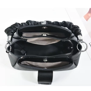 Internal detail of black pebbled leather handbag with ruched handle and multiple pockets