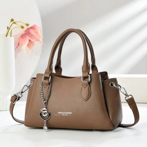 Detail of brown litchi pattern leather handbag with heart pendant and detachable strap