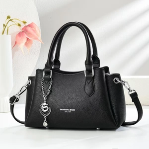 Close-up of black lychee grain leather handbag with silver heart charm and metal feet