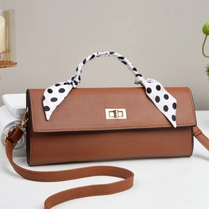 Detail of caramel brown textured handbag with gold lock and polka dot scarf decoration