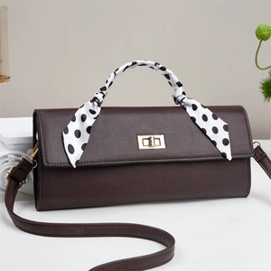 Detail of dark brown leather handbag featuring a polka dot scarf handle and gold twist lock