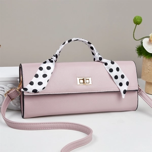 Close-up of pink lychee textured leather bag with polka dot scarf and gold clasp