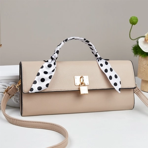 Detail of beige litchi leather handbag with polka dot scarf and golden metal lock