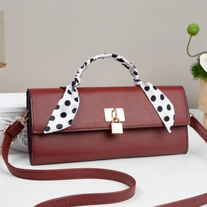 Detail of wine red lychee leather handbag with gold buckle and polka dot silk scarf