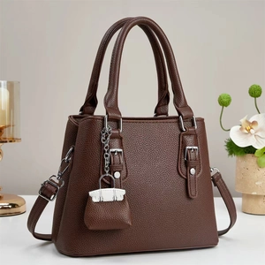 Brown lychee leather Boston handbag for women with silver hardware and mini charm