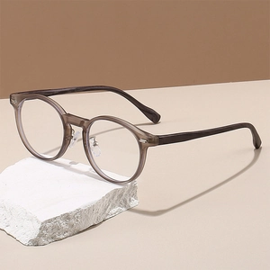 Detailansicht der runden, grauen Brille mit silbernem Metallscharnier und Nasenpads