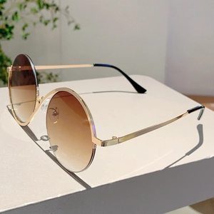 Détail de lunettes de soleil rondes rétro en métal doré avec verres dégradés marron