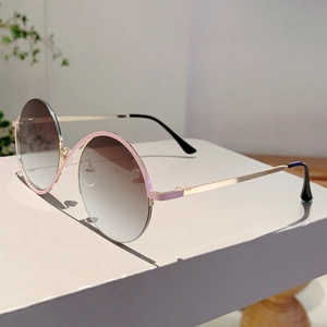 Détail de lunettes de soleil rondes oversize avec branches dorées et accents roses