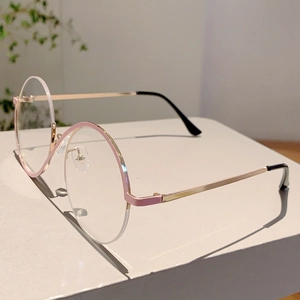 Détail de lunettes de soleil rondes demi-cerclées roses avec branches dorées