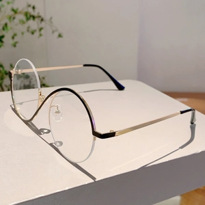 Détail de lunettes de soleil rondes rétro demi-cerclées noir et or sur présentoir gris