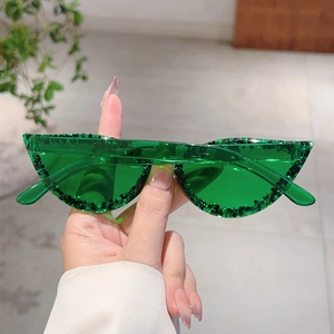 Détail de lunettes de soleil œil-de-chat vertes avec texture pailletée noire au bord