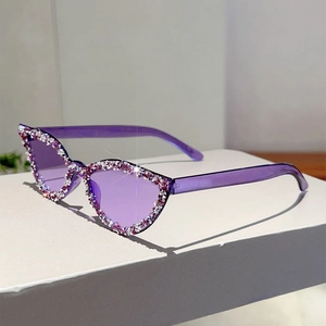 Détail de lunettes de soleil œil-de-chat violettes ornées de strass roses et blancs