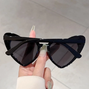 Detailansicht der schwarzen herzförmigen Sonnenbrille mit Strasssteinen und dunklen Gläsern