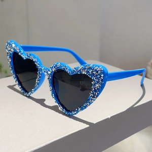 Detail einer herzförmigen Sonnenbrille mit blauem Rahmen und funkelndem Strass-Besatz