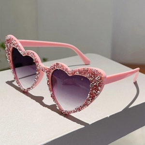 Detail der rosa herzförmigen Sonnenbrille mit Strasssteinen und lila Verlaufsgläsern