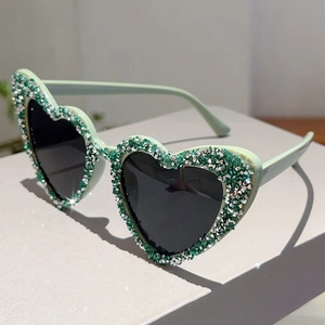 Detailansicht der herzförmigen Sonnenbrille mit hellgrünem Rahmen und glitzernden Steinen