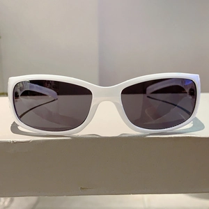 Detail view of white frame sunglasses with dark gray lenses on a minimalist background