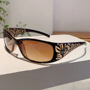 Detail of sunglasses with black frames and gold floral rhinestone patterns on the temples
