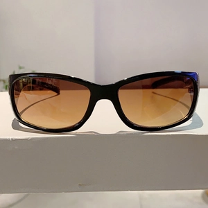 Close-up of black sunglasses with brown gradient lenses and glossy streamlined frame