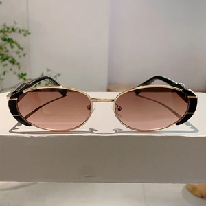 Détail de lunettes de soleil ovales en métal doré avec verres dégradés roses