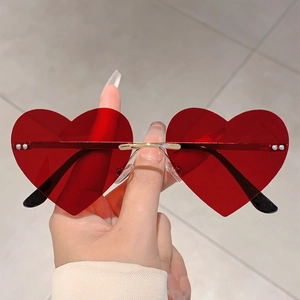 Detail of red heart-shaped rimless sunglasses with gold metal bridge for trendy party wear
