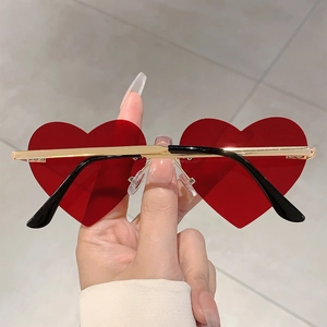 Detail view of heart-shaped sunglasses with deep red lenses and gold-black metal frame