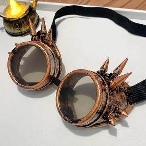 Detail of bronze steampunk goggles with spikes and vintage lantern on a light surface