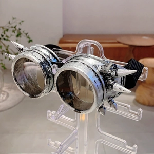 Detail of silver steampunk goggles with metallic spikes on a clear display stand