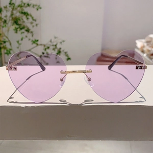 Close-up of heart-shaped rimless sunglasses with purple lenses and gold metal frame