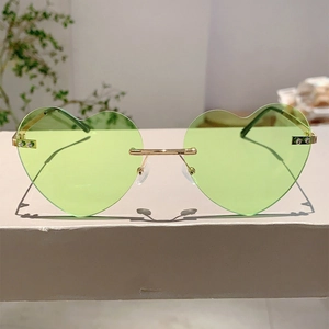 Detail of heart-shaped green jelly sunglasses with gold metal temples and clear nose pads