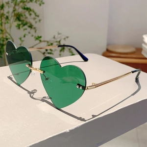 Detail view of heart-shaped rimless sunglasses with green lenses and gold metal frames