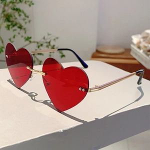 Detail of red heart-shaped rimless sunglasses with elegant gold metal temples on a table