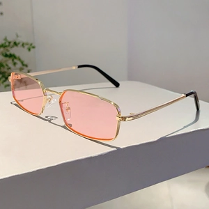 Dettaglio di occhiali da sole vintage con montatura in metallo dorato e lenti rosa
