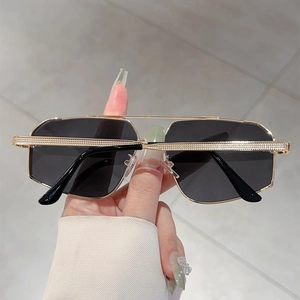 Detail of gold metal sunglasses with woven texture on the frame and dark lenses