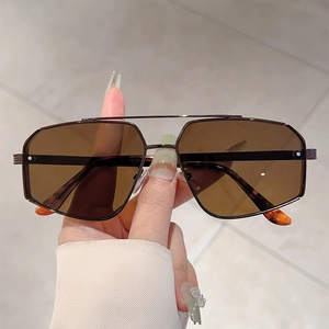 Detail of retro pilot sunglasses featuring brown gradient lenses and slim black metal frame