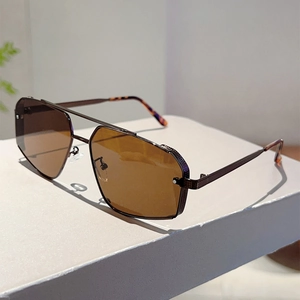 Detail of pilot sunglasses featuring brown metal frames and double bridge on white box